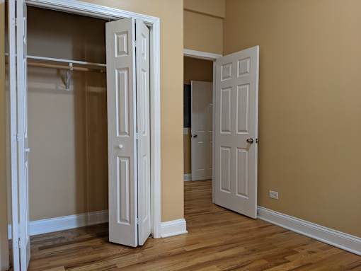 A room with a white door and a wooden floor.