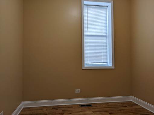 A room with a window and wooden flooring.