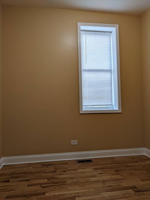 A room with a window and wooden flooring.