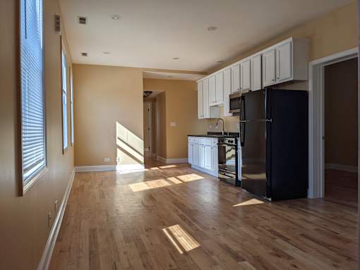 A kitchen with wooden floors and a black refrigerator.