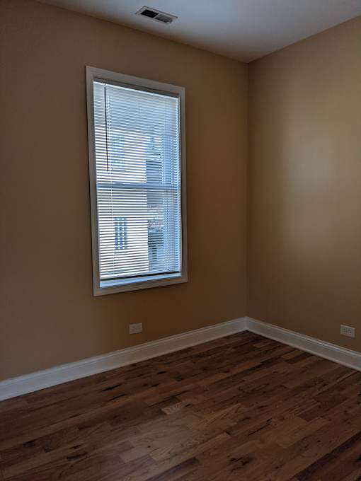 A room with a window and wooden flooring.