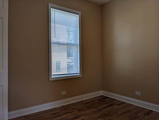 A room with a window and wooden flooring.