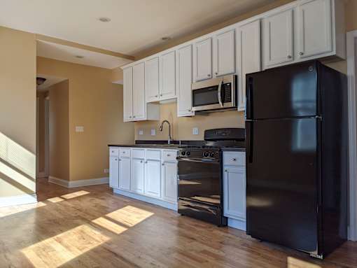 A kitchen with black appliances and white cabinets.