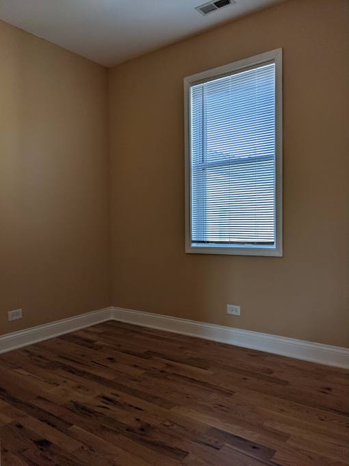 A room with a window and wooden flooring.