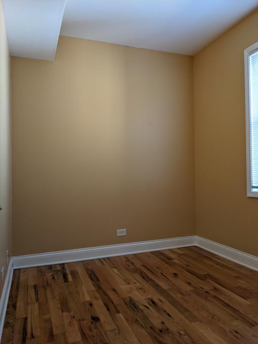 A room with wooden flooring and a window on the wall.