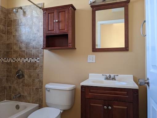A white toilet sits under a mirror in a bathroom.