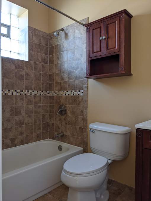 A white toilet sits next to a bathtub in a bathroom.