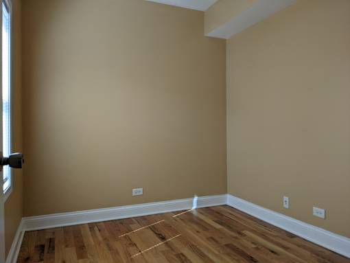 A room with wooden flooring and beige walls.