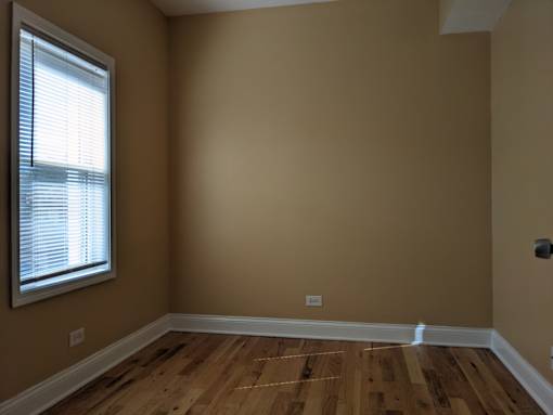 A room with wooden flooring and a window with blinds.