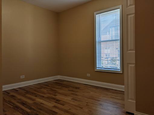 A room with a window and wooden flooring.