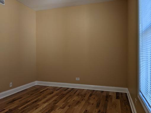 A room with wooden flooring and a window with blinds.