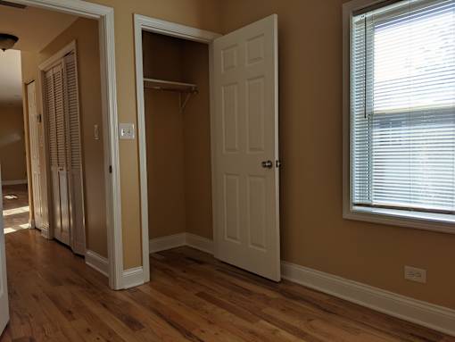 A room with a white door and a window with blinds.