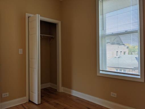 A room with a white door and a window with blinds.