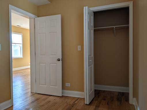 A white door is open to a room with a wooden floor.