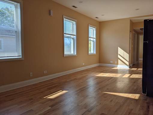 A room with wooden floors and two windows.