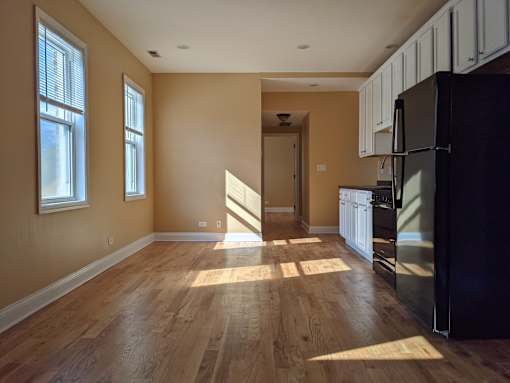 A kitchen with a black refrigerator and wooden floors.