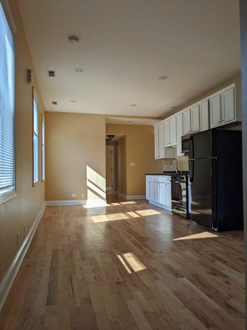 A kitchen with wooden floors and white cabinets.