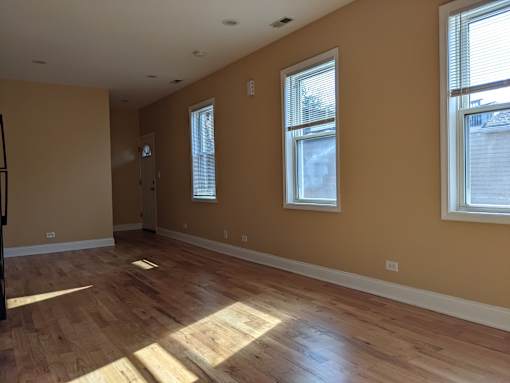 A room with wooden floors and three windows.