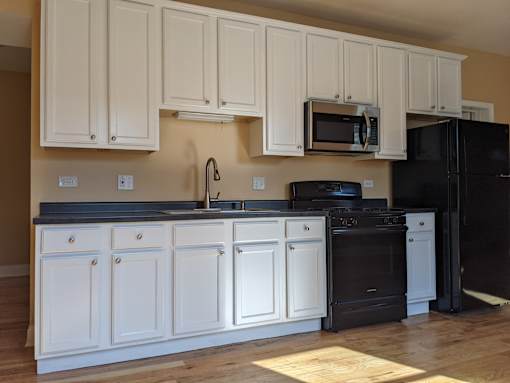 A kitchen with black appliances and white cabinets.
