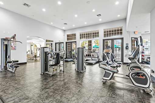 A gym with a variety of equipment including treadmills, weights, and exercise machines.
