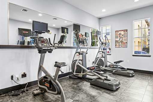 A gym with a mirror, treadmills, and exercise bikes.
