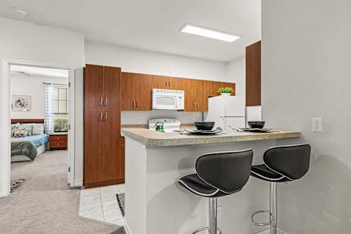 A kitchen with a counter and two chairs.