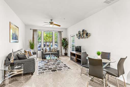 A living room with a grey couch, a glass coffee table, and a television.