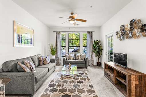 A living room with a grey couch, a coffee table, and a ceiling fan.