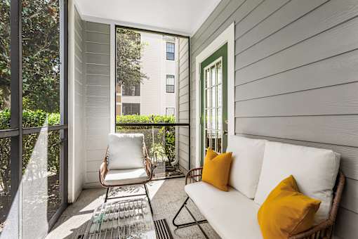 A white couch with two yellow pillows sits on a patio.
