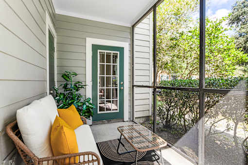 A patio with a wicker chair and a table.