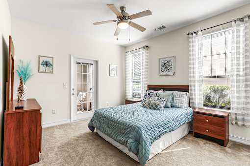 A bedroom with a bed, dresser, and ceiling fan.