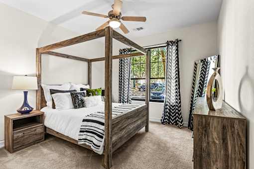 A bedroom with a four poster bed and a ceiling fan.