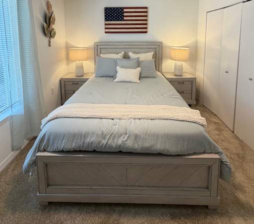 A bedroom with a large bed and an American flag on the wall.
