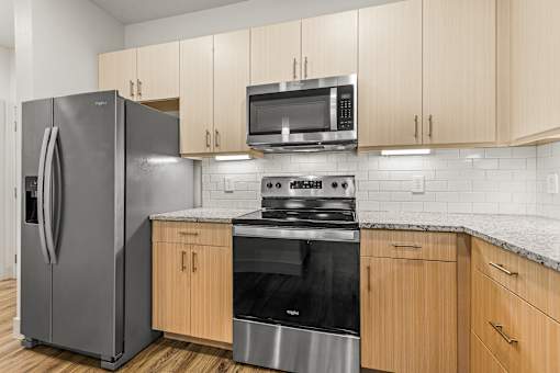 A kitchen with a refrigerator, microwave, oven, and cabinets.