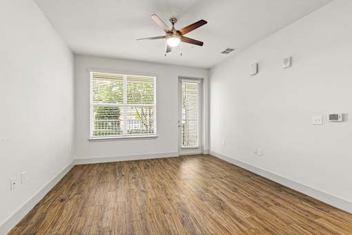 A room with a ceiling fan and wooden flooring.