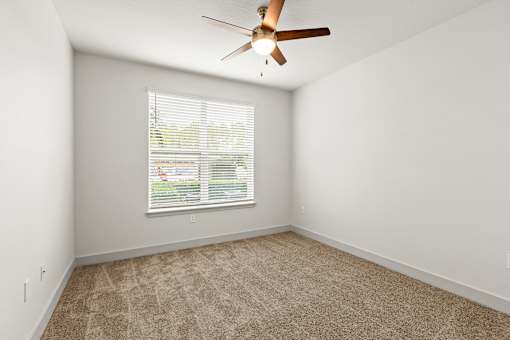 A room with a ceiling fan and a window with blinds.