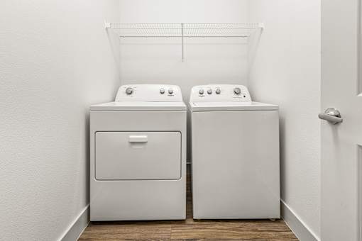 Two white front loading washing machines in a laundry room.
