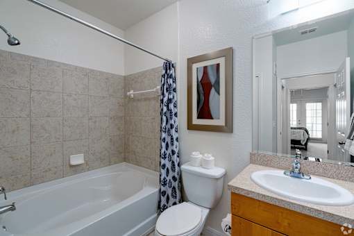 A bathroom with a white toilet, a white sink, a white bathtub, and a shower curtain.