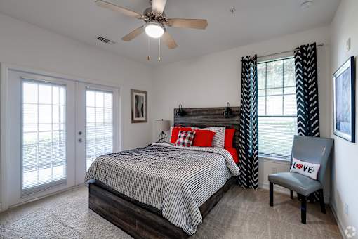 A bedroom with a bed, chair, and ceiling fan.