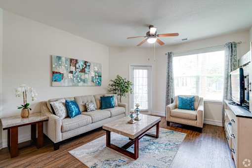 A living room with a beige couch, a coffee table, and a ceiling fan.