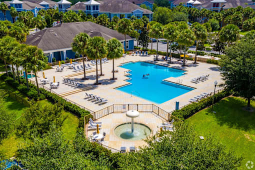 A large swimming pool surrounded by trees and a hot tub.