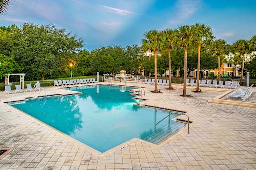 A large swimming pool surrounded by palm trees and lounge chairs.