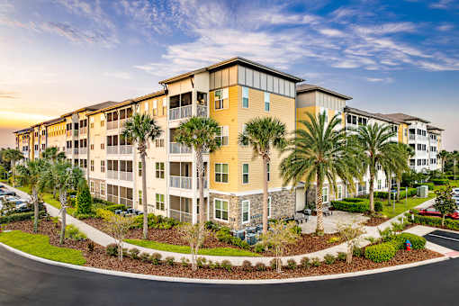 A large apartment complex with a parking lot in front.