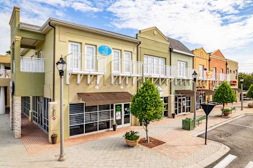 A street view of a shopping area with a blue sign on the building.