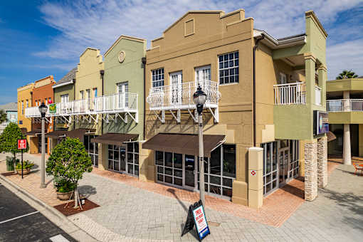 A street view of a row of colorful buildings with balconies and a tree in a planter.