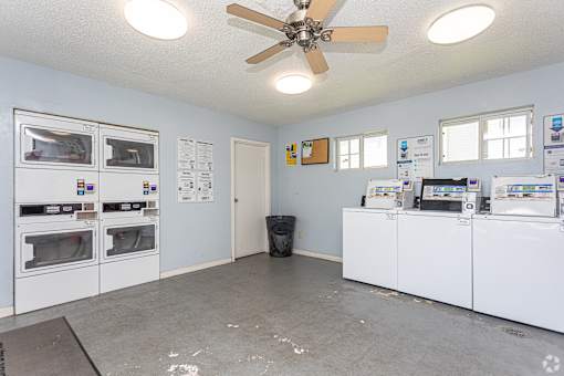 A room with a ceiling fan and a wall of ovens.
