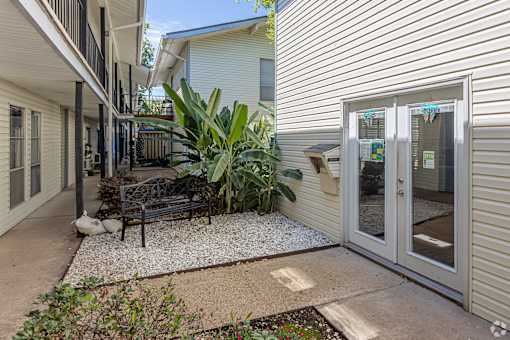 A patio area with a bench, plants, and a door.