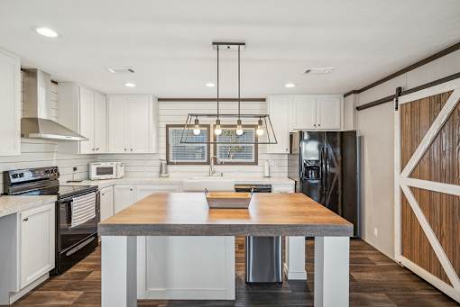 A modern kitchen with a wooden island in the center.