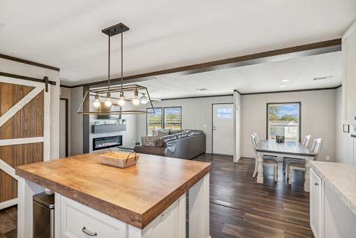 A kitchen with a wooden island and a dining table with chairs.