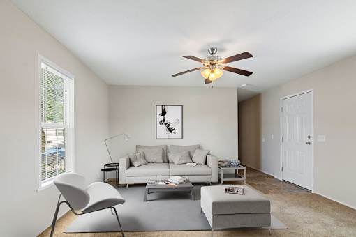 Model living room with couch and ceiling fan at Candlelight Village Manufactured Home Community in Sauk, IL
